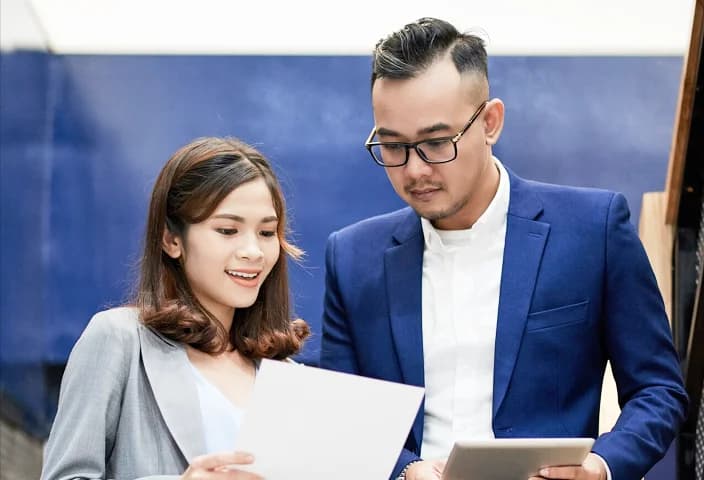Profesional korporasi sedang meninjau dokumen dan berdiskusi.
